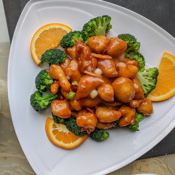 Ying Li Restaurant's orange chicken with broccoli florets and orange slices on a white plate.